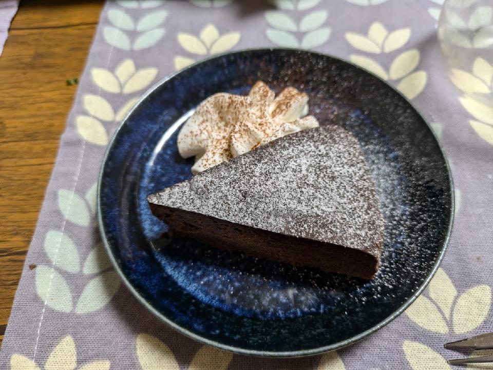 Baked chocolate cake dusted with cocoa on a serving board